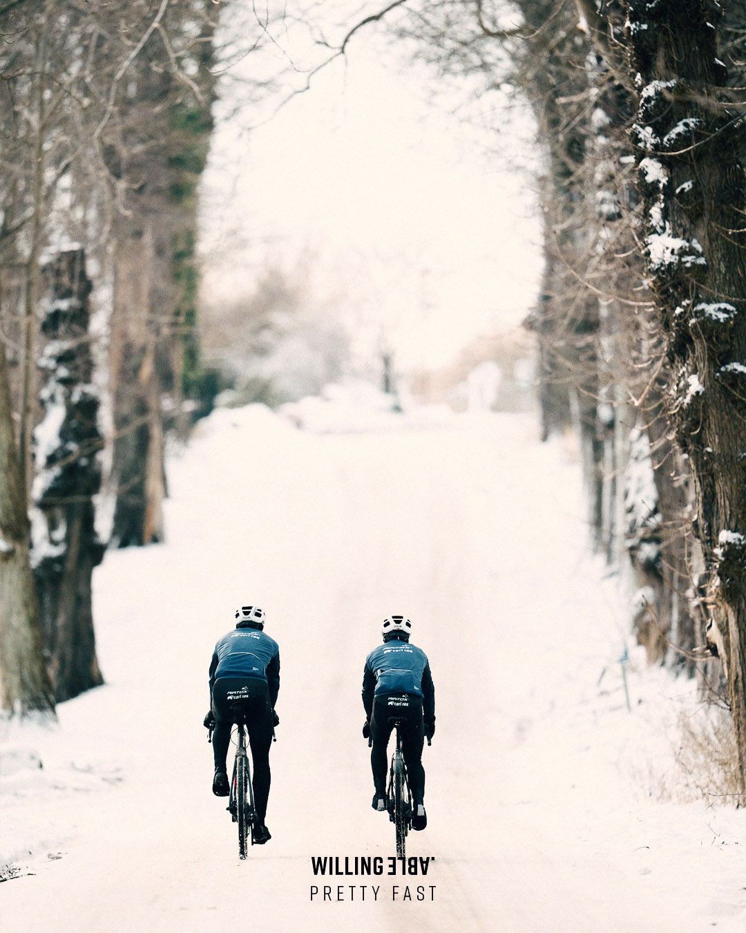 Cyclists from Team Airtox in a winter race wearing Willing Able apparel. Cycling through a forrest in the snow.