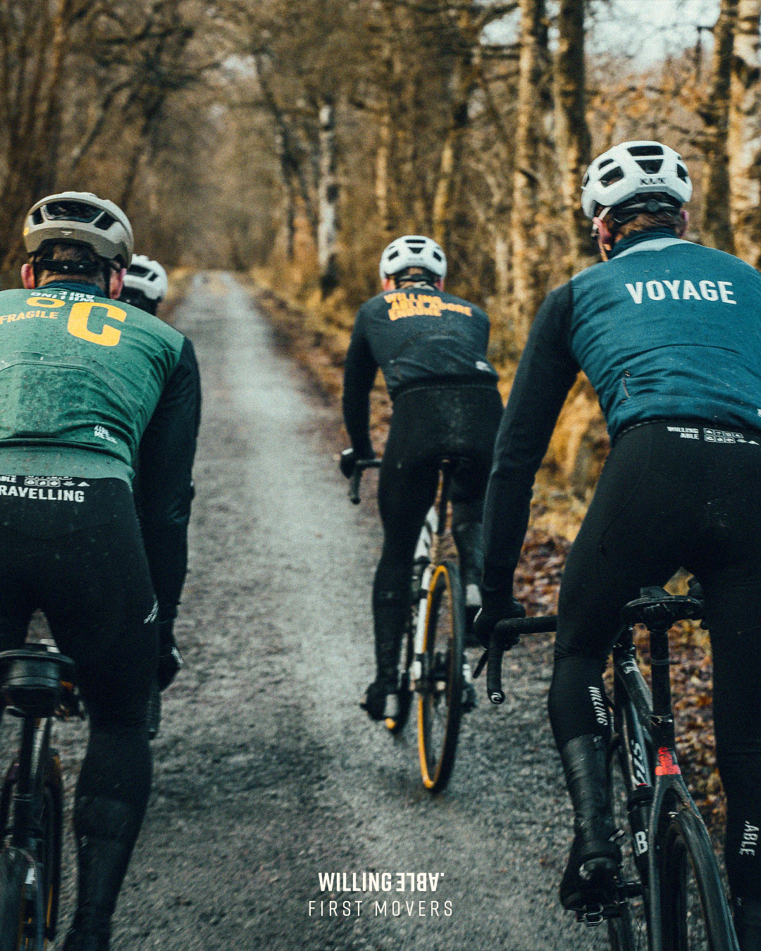 Three cyclists for Willing Able dricing down a road in the forrest.