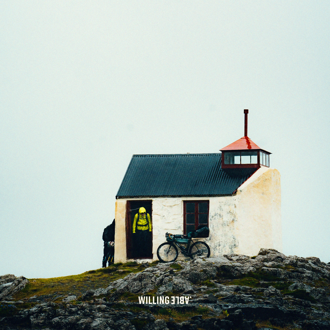 A house in Iceland with a bike in front of it, and the text Willing Able written on the ground in front of the house and bike.